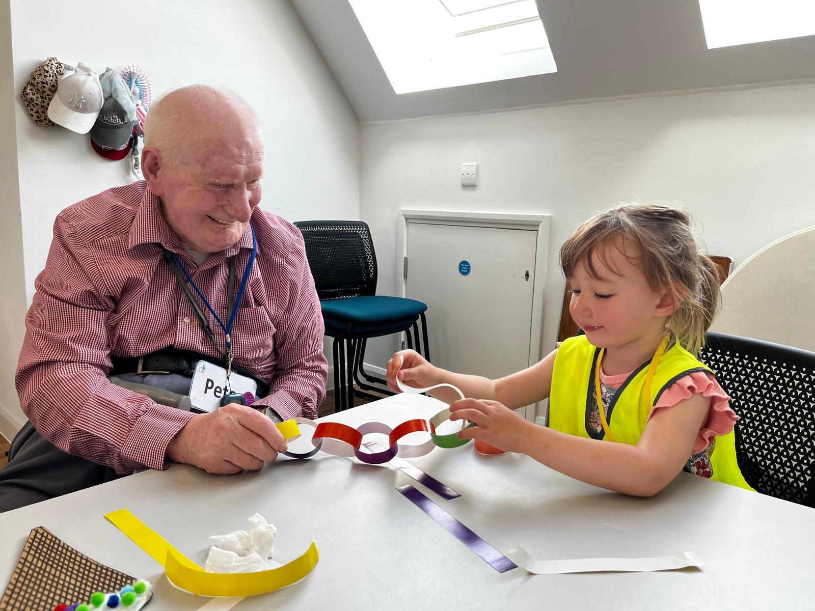 An older adult and child making a paper chain